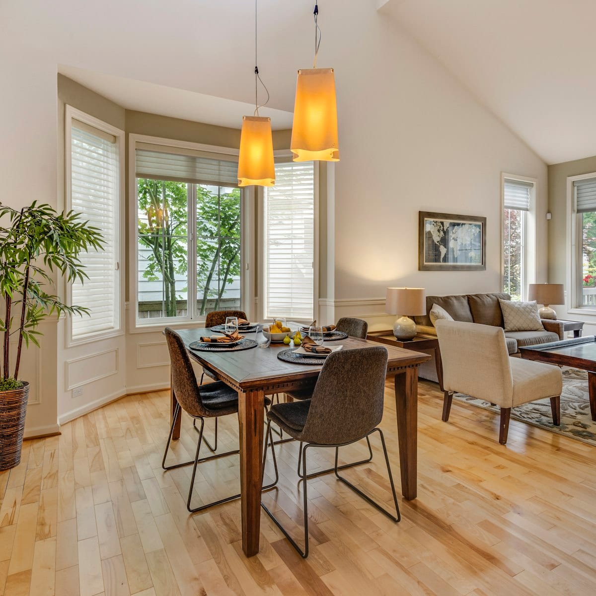 Conjunto de mesa de jantar de 4 lugares com cadeiras estofadas em sala clara com luminárias pendentes